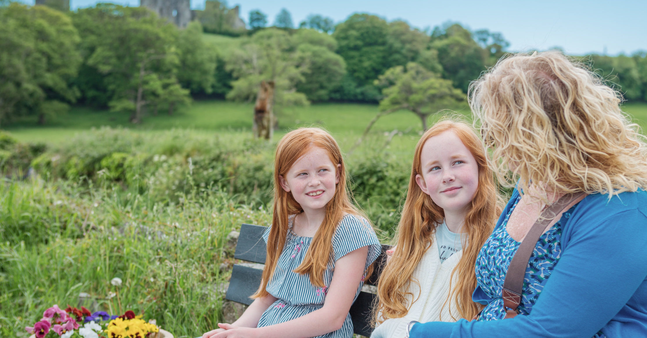 While sitting on the bench, two children listen to an adult woman